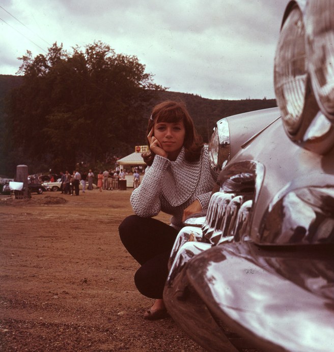 Ronnie Haran in the 1960s, crouched beside a vintage car